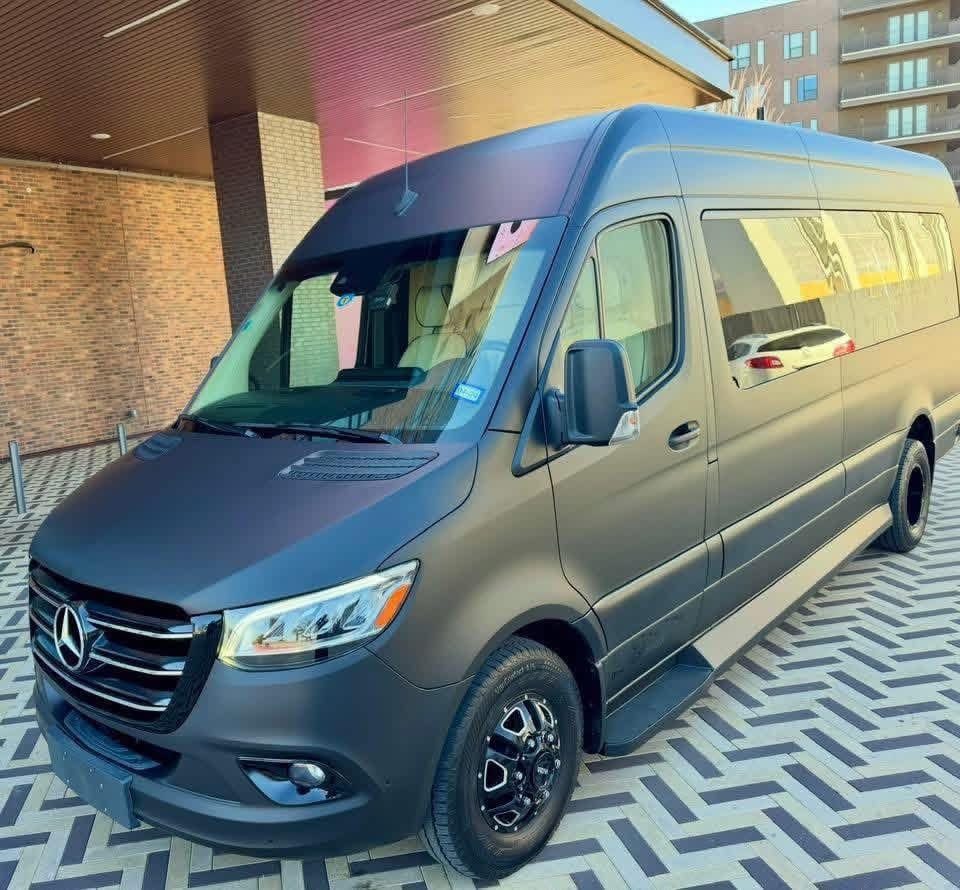 Black Mercedes-Benz Sprinter passenger van under a building canopy — Excalibur 15 passenger van transportation, Oklahoma